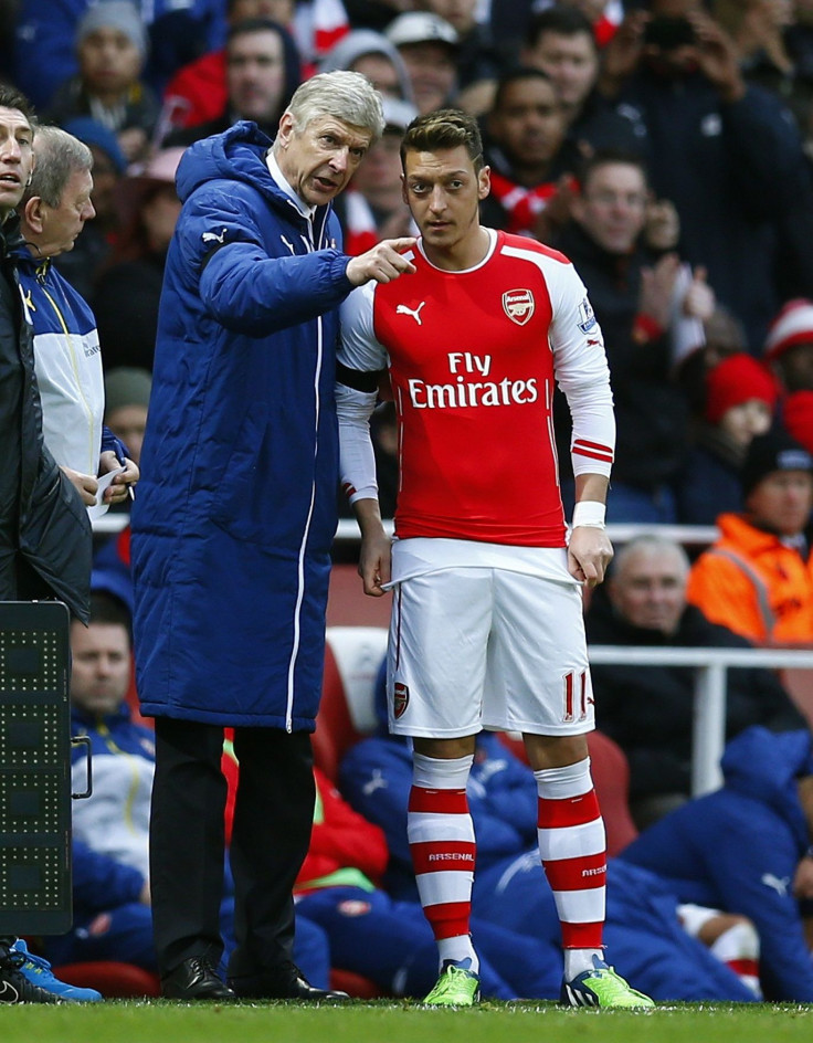 Arsenal's Mesut Ozil receives instructions from manager Arsene Wenger