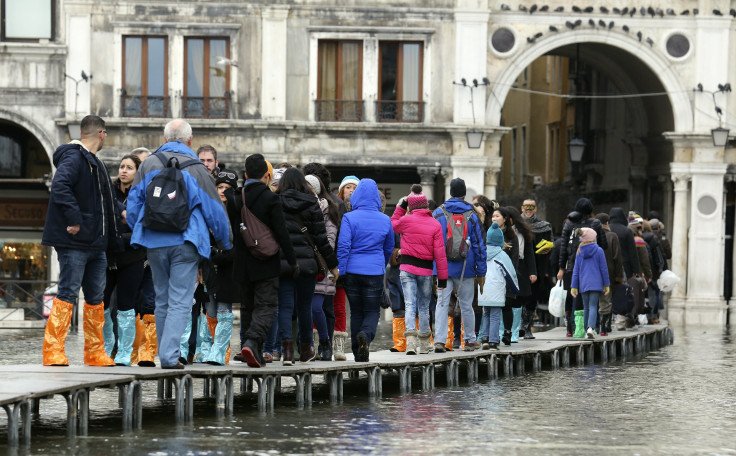 Tourists walk on raised platforms above flood waters during a period of seasonal high water and on the first day of carnival, in Venice February 1, 2015.