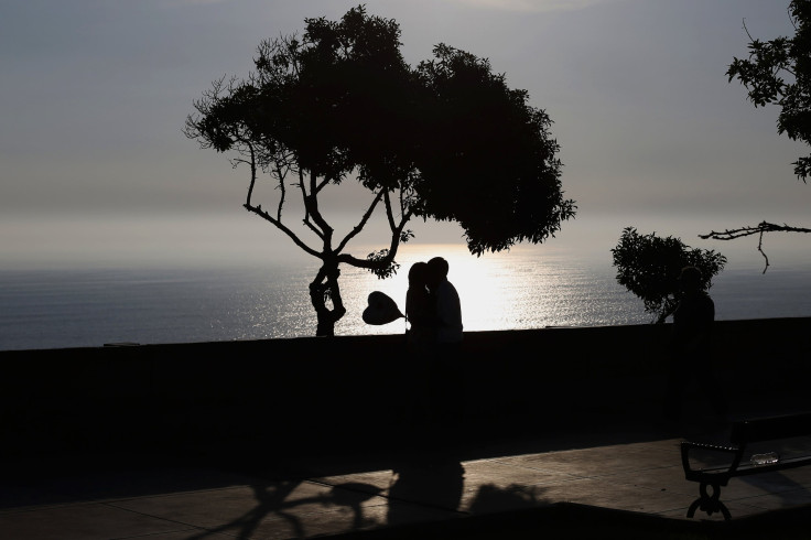 A couple kisses while holding a heart-shaped balloon at an ocean-front in the neighbourhood of Miraflores in Lima January 28, 2015. 