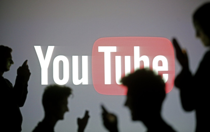 People are silhouetted as they pose with mobile devices in front of a screen projected with a Youtube logo, in this picture illustration taken in Zenica October 29, 2014.