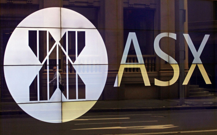 An office worker walks past the board of the Australian Securities Exchange building displaying its logo in central Sydney April 5, 2013.