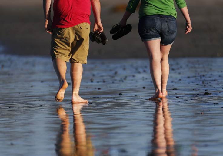 A couple carry their shoes as they walk barefoot along the beach in Cardiff, California February 12, 2015.  