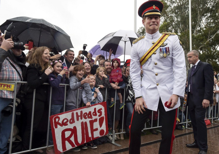Britain's Prince Harry reacts as he shakes hands with members of the public displaying a sign reading 'Red Heads Rule' after visiting the Australian War Memorial in Canberra April 6, 2015.
