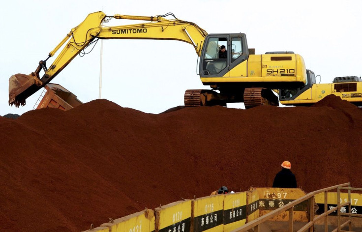 A worker operates an excavator on a pile of iron ore at the dump site of a port in Lianyungang, Jiangsu province, January 12, 2015.