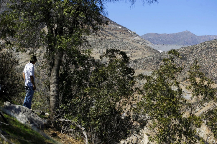 A local is seen on a hill in front of a waste deposit tank (R) of Los Pelambres mine near the Pupio estuary on the road to Caimanes town at the El Mauro valley, April 1, 2015.