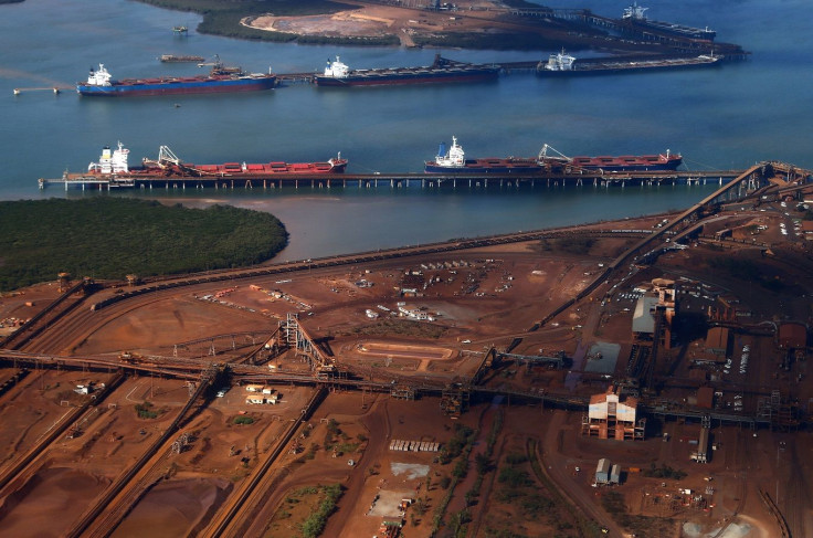Ships waiting to be loaded are seen near piles of iron ore and bucket-wheel reclaimers at the Fortescue loading dock located at Port Hedland in the Pilbara region of Western Australia December 3, 2013.