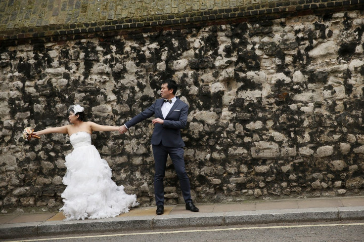 A couple wearing wedding outfits pose for a photograph in central London March 19, 2015.