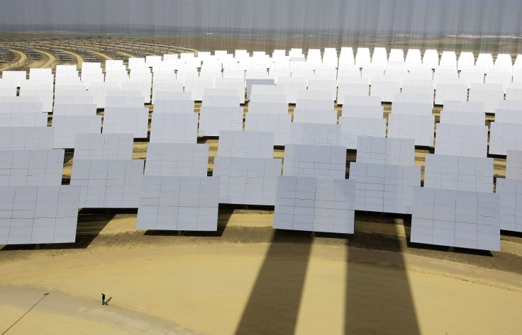 A man walks next to solar panels (bottom L) at a soon-to-be completed solucar solar park at Sanlucar La Mayor, near Seville, February 13, 2008.