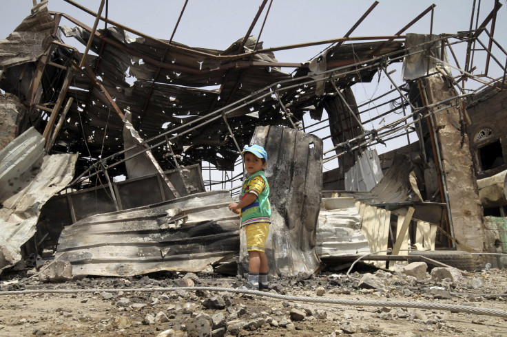 A boy waits for his father in front of a damaged factory 