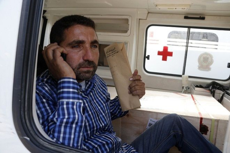 A man carrying official documents sits in an ambulance next to a coffin 