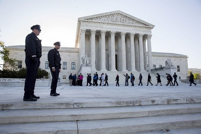 Police watch as members of the public enter the Supreme Court