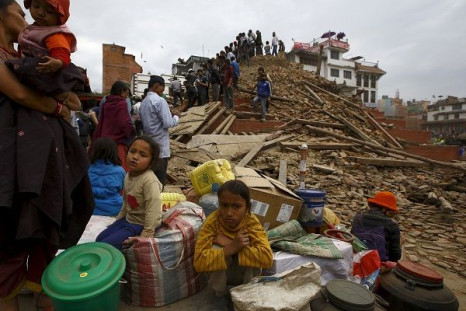 People sit with their belongings outside a damaged temple 