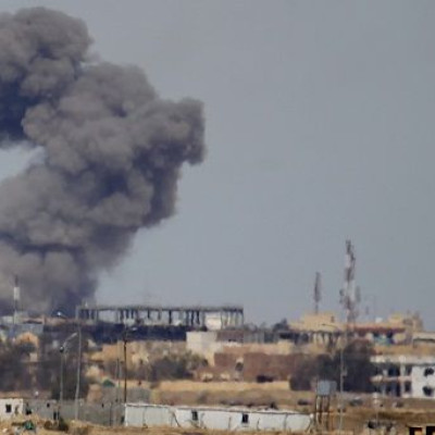 A plume of smoke rises above a building during an air strike 