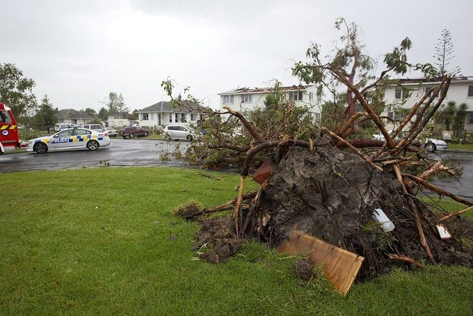 Police patrol the roads amid the devastation in the suburb of Hobsonville after a tornado