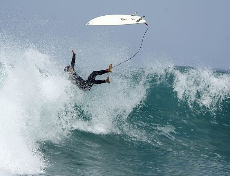 A surfer falls off his board 