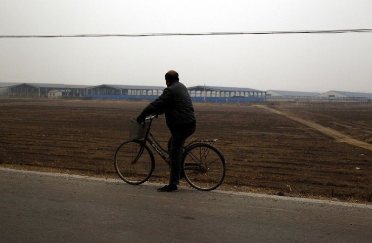 A local farmer sits on his bicycle as he looks at a 40-hectare farm 