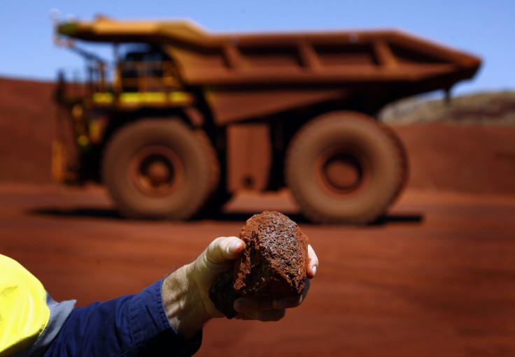 Fortescue Chief Executive Officer (CEO) Nev Power holds a piece of iron ore in front of a remote-controlled truck at the Fortescue Solomon iron ore mine