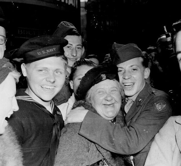 An American soldier hugs an English woman and as crowds celebrate Germany's unconditional surrender