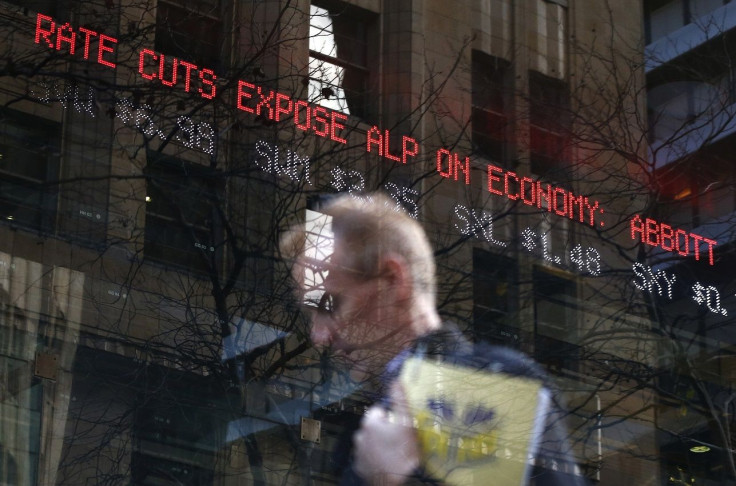 A man walks in front of an electronic board with news on the interest rates in central Sydney August 6, 2013.