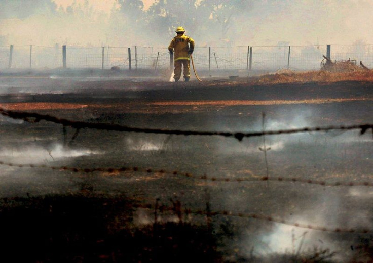 A fire-fighter tries to put out a fire threatening homes in the western Sydney suburb of Minchinbury, October 23 2002. 