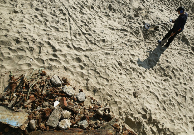 A man uses a metal detector to look for gold on the outer harbour beach at Folkestone in southeast England September 4, 2014.