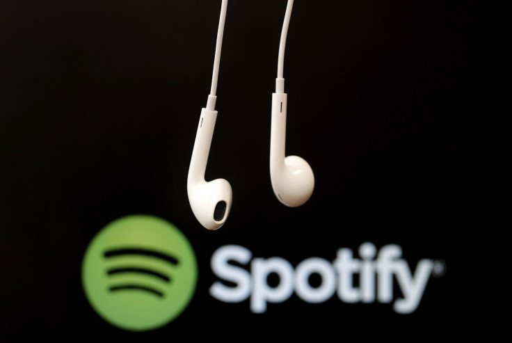 Headphones are seen in front of a logo of online music streaming service Spotif