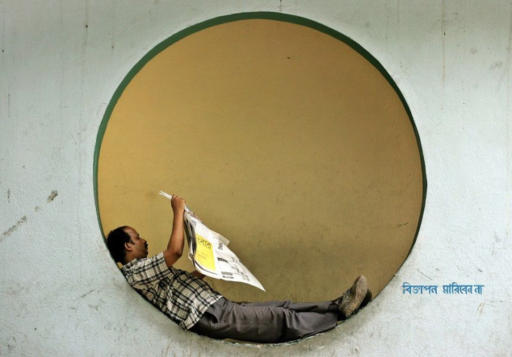 A man reads a newspaper while resting on a wall in the eastern Indian city of Kolkata July 5, 2006.