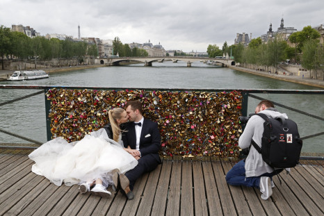 A recently-married couple from Poland, Dominika and Bartek Mieczkowski, kiss as they pose for their own photographer in front of an iron grill covered with "love locks" on the Pont de Arts over the River Seine in Paris, France, May 31, 2015. 