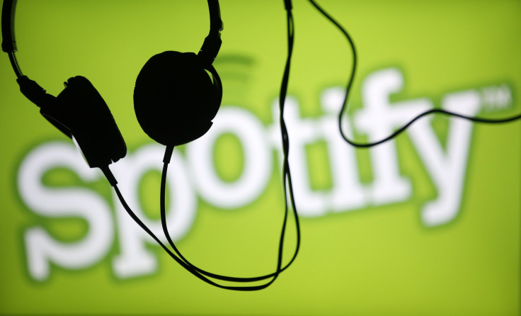 Headsets hang in front of a screen displaying a Spotify logo