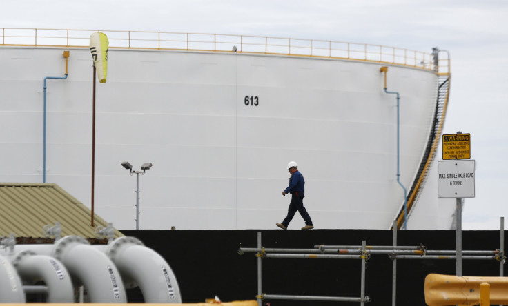 A worker passes by a large oil reservoir in Sydney'
