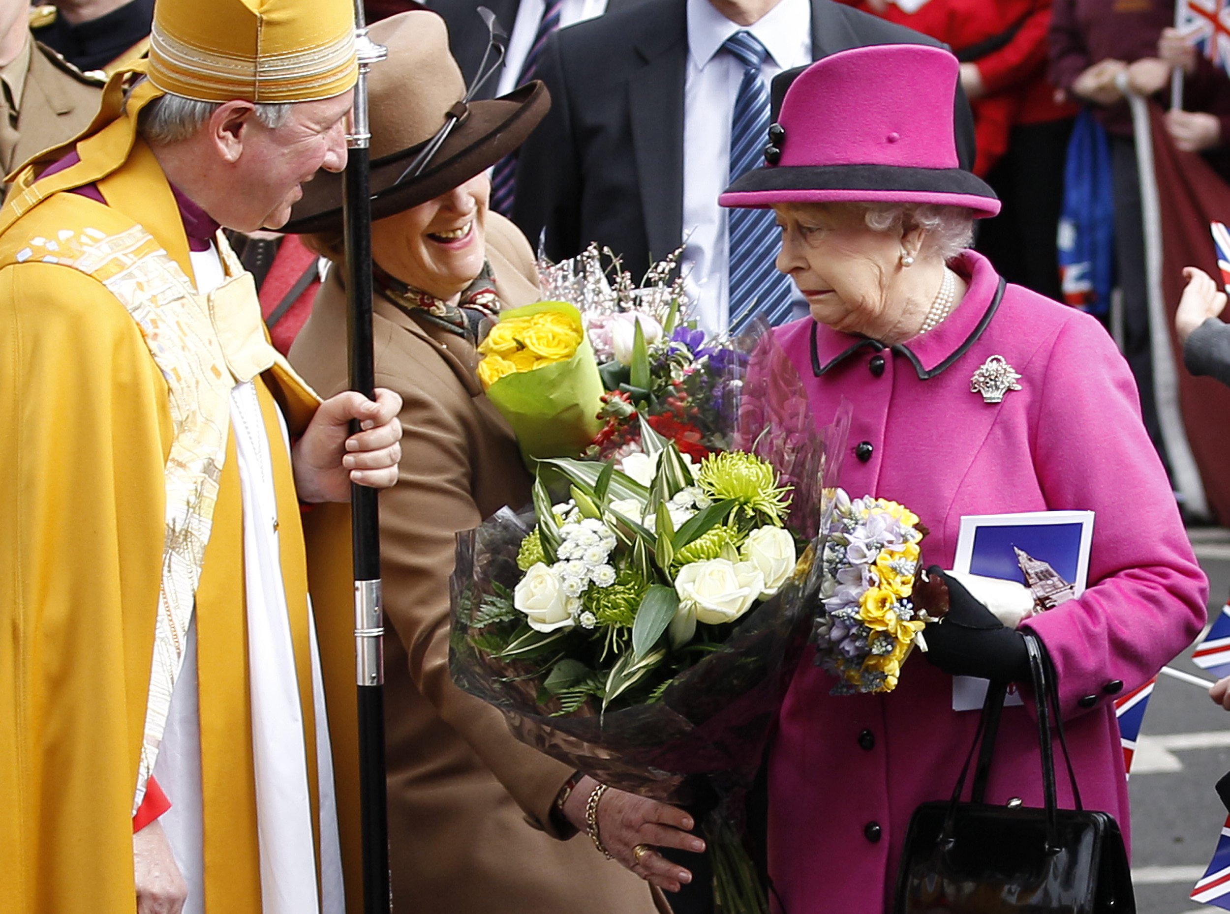 1111 Britains Queen Elizabeth reacts after receiving a heavy bunch of flowers during a visit to the Cathedral in Leicester