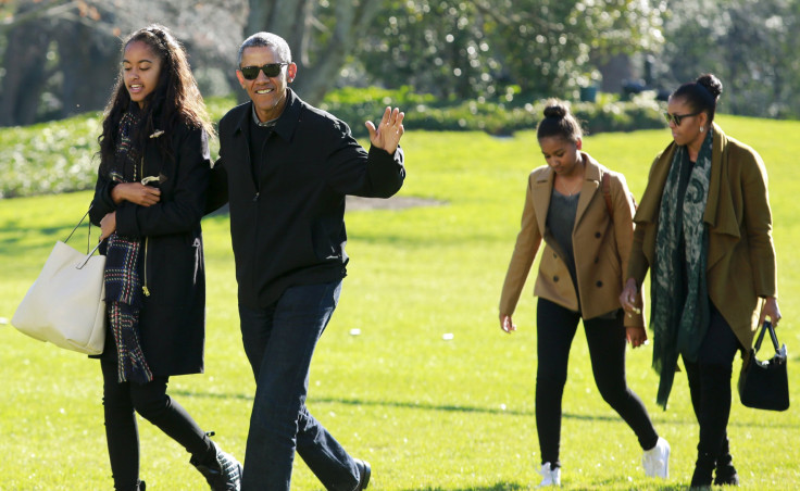 U.S. President Barack Obama waves as he walks with first lady Michelle Obama (R) and their daughters Malia (L) and Sasha