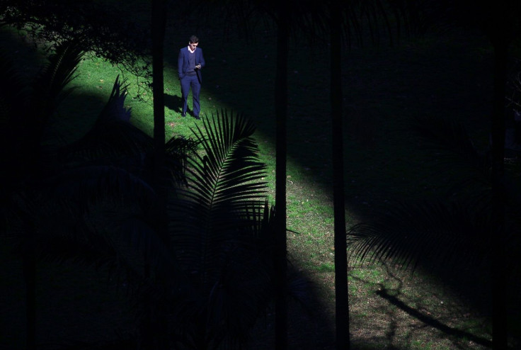 A businessman checks his mobile phone as the sun filters through a Sydney park August 4, 2014.
