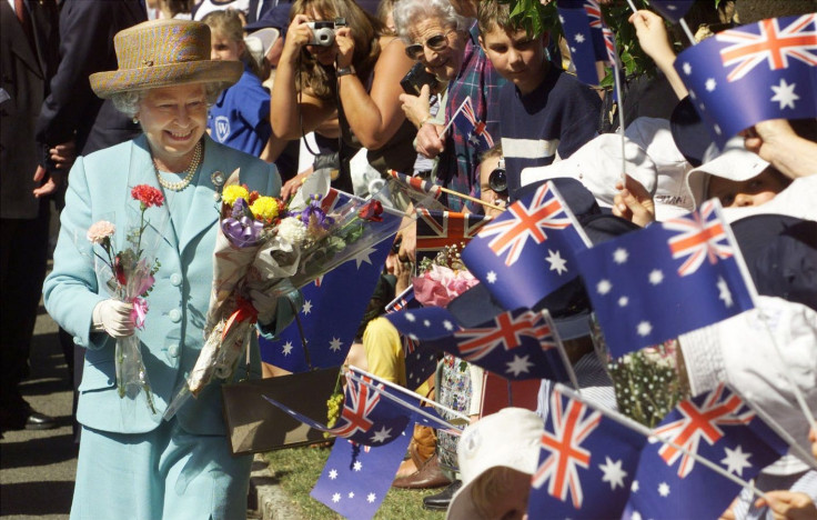 Britain's Queen Elizabeth (L) smiles as she accepts flowers and gifts from flag waving children as she arrives at Launceston March 29.