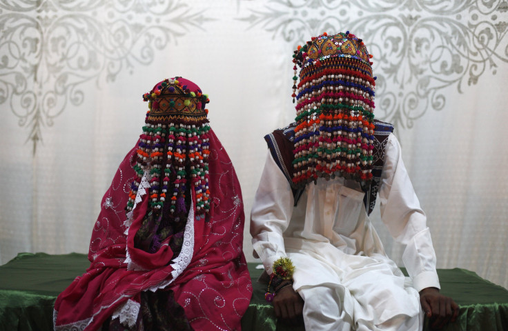 A bride and groom wearing traditional garlands, made of beads and cotton threads, on their foreheads, wait for their wedding to start during a mass marriage ceremony in Karachi.