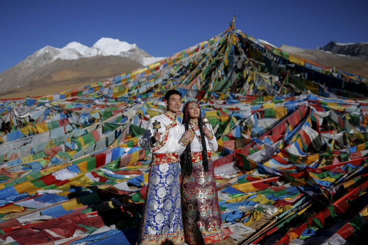 Jing Li (L) and her husband Ke Xu wear Tibetan traditional costumes as they pose for their wedding photos in front of Tibetan prayer flags at the Nianqing Tanggula mountain pass in the Tibet Autonomous Region. 
