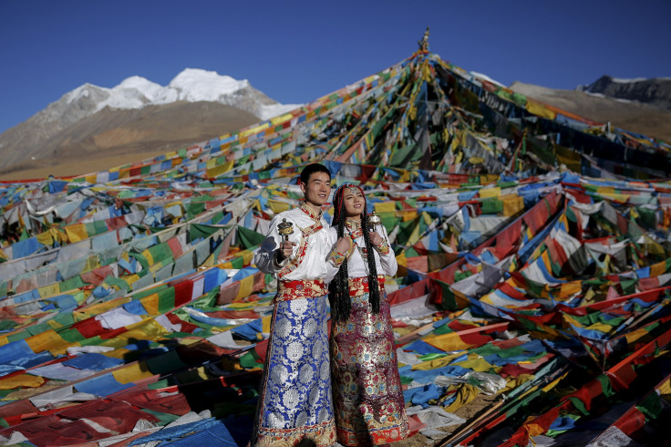 Jing Li (L) and her husband Ke Xu wear Tibetan traditional costumes as they pose for their wedding photos in front of Tibetan prayer flags at the Nianqing Tanggula mountain pass in the Tibet Autonomous Region.