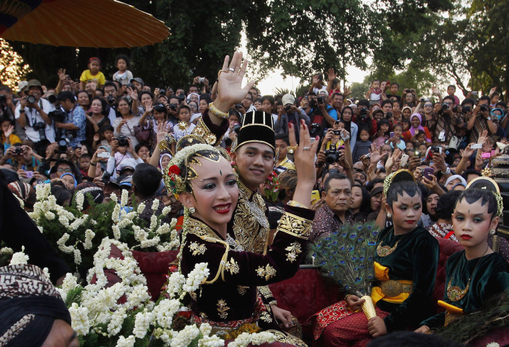 Kanjeng Pangeran Haryo (KPH) Yudanegara and his wife Gusti Kanjeng Ratu (GKR) Bendara wave to the crowd in a horse-drawn carriage in Yogyakarta. 