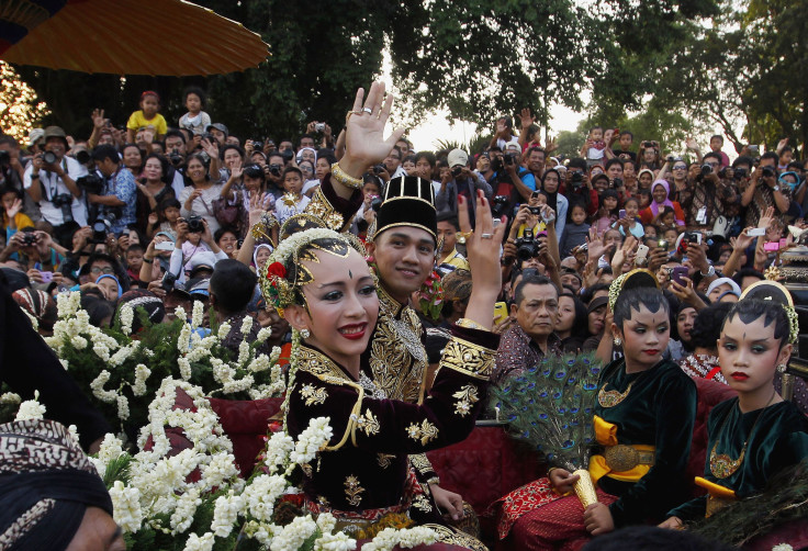 Kanjeng Pangeran Haryo (KPH) Yudanegara and his wife Gusti Kanjeng Ratu (GKR) Bendara wave to the crowd in a horse-drawn carriage in Yogyakarta.