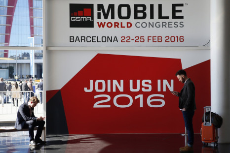People look at their mobiles in front of the 2016 Mobile World Congress edition banner in Barcelona March 5, 2015. 