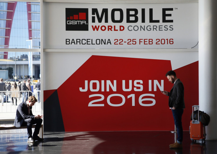 People look at their mobiles in front of the 2016 Mobile World Congress edition banner in Barcelona March 5, 2015. 