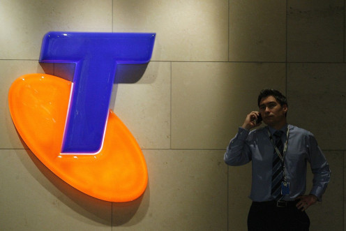 A man uses his mobile phone in front of a Telstra Logo in central Sydney August 13, 2009.