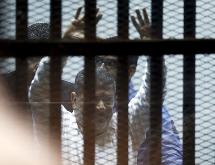 Ousted Egyptian President Mohamed Mursi gestures after his trial behind bars at a court in the outskirts of Cairo, April 21, 2015.
