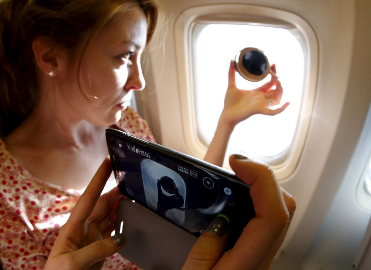 People take pictures onboard a plane during the so-called "Eclipse Flight" from the Russian city of Murmansk, to observe the solar eclipse above the neutral waters of the Norwegian Sea, March 20, 2015.