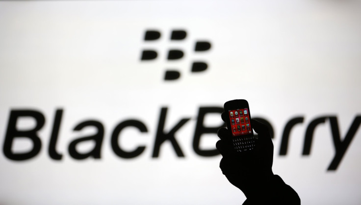 A man is silhouetted against a video screen with the Blackberry logo as he pose with a Blackberry Q10 in this photo illustration taken in the central Bosnian town of Zenica, September 21, 2013. 