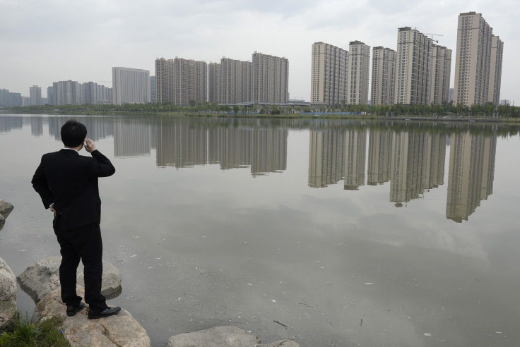 A man talks on his phone near a new residential compound in Taiyuan, Shanxi province, May 11, 2014.