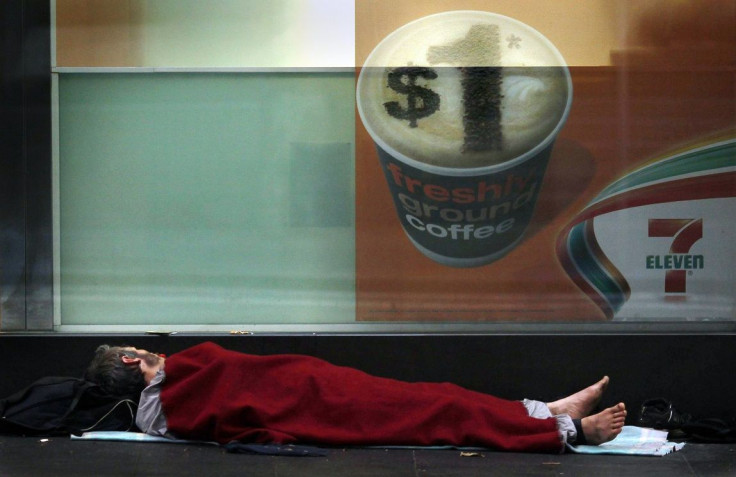 A homeless man sleeps under a blanket on the pavement outside a convenience shop in central Sydney March 15, 2012.