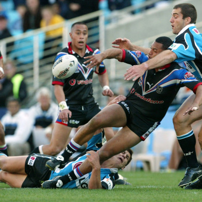 New Zealand Warriors Ali Lauiti'iti unloads the ball as he is tackled by Cronulla Sharks Paul Mellor (R) during the National Rugby League second preliminary final against the Cronulla Sharks in Sydney September 29, 2002.