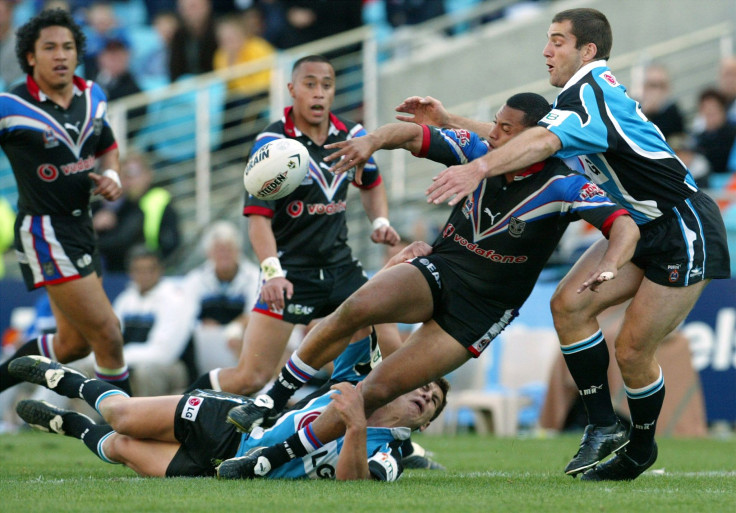 New Zealand Warriors Ali Lauiti'iti unloads the ball as he is tackled by Cronulla Sharks Paul Mellor (R) during the National Rugby League second preliminary final against the Cronulla Sharks in Sydney September 29, 2002.