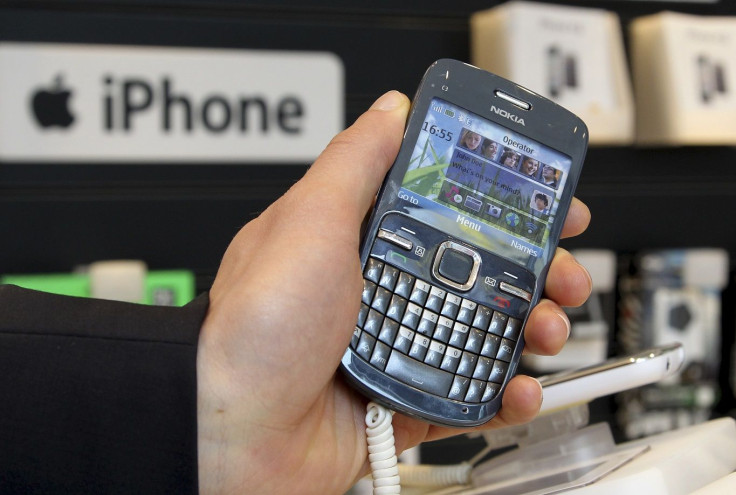 A Nokia mobile phone is pictured near an iPhone logo in a shop in Brussels April 12, 2012.
